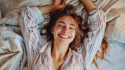 young happy woman in pajama stretching her arms and smiling while sitting on bed after sleep or nap