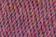 A close up of a purple and yellow yarn. The yarn is knotted and has a fuzzy texture