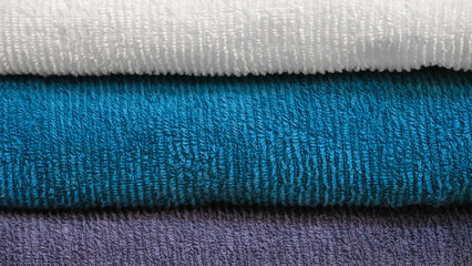 Leinwandbilder - Multi-colored textile towels lie in a stack on a shelf