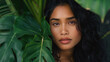 Portrait of a beautiful young Hawaiian woman standing among the leaves of a large plant. An elegant model with long dark hair.