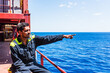 © Mariusz - Lonely seafarer on board of the cargo ship, he is looking into the open sea and pointing spotted target on the horizon.