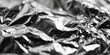 Crumpled foil close-up. Macro shooting of mashed metal paper. Silver background texture. Abstract monochrome overlay background black and white silver effect. Texture of shiny piece aluminium foil