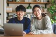 Asian young couple is playing on a laptop