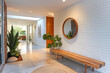 Mid century interior design of modern home entryway with wooden bench against white brick wall.
