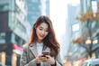 Asian woman holding smart phone on urban street