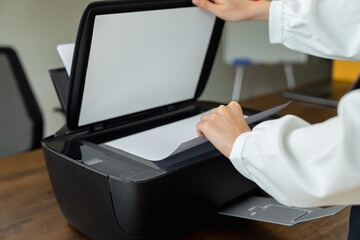 Hand press button on printer with copy, print, scan and fax document and paperwork in office.