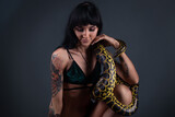 Fototapeta Las - Photo of the young brunette woman sitting with yellow anaconda
