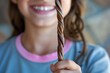 smiling girl holding a long twisted licorice piece