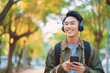 Asian man is listening to music on smartphone with headphones outdoors