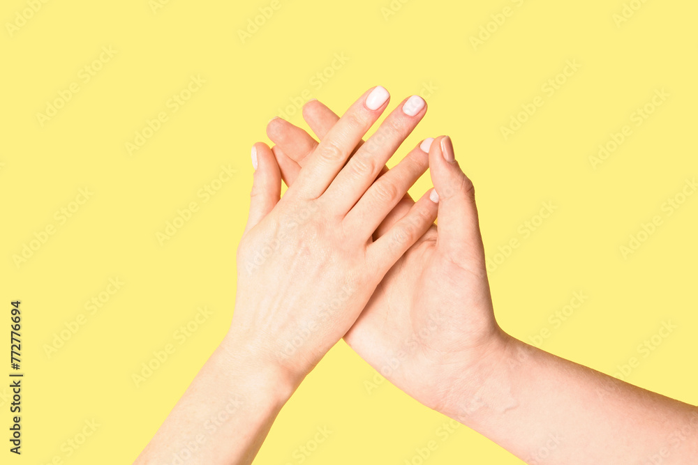 Women holding hands together on yellow background. Friendship concept