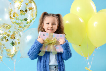 Wall Mural - Cute little girl with balloons and gift box on blue background