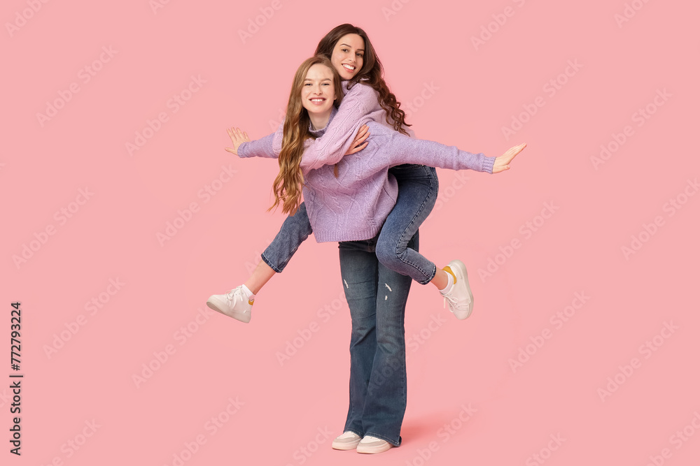 Happy young sisters on pink background