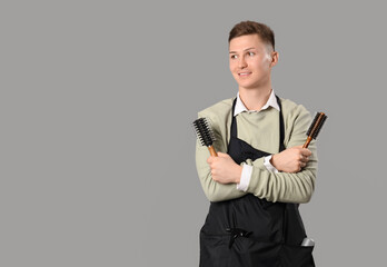 Wall Mural - Male barber with hair brushes on grey background