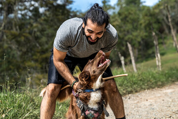 adult male mongrel playing happily with his border collie dog and congratulating him for learning new tricks