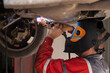Mechanic repairs car in a car repair station. Manual welding of auto parts.