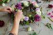 person crafting a wreath with artificial flowers and twigs