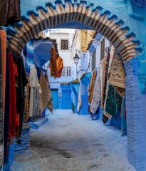 Wall Mural - arched doorway with colourful carpets on the wall in the historic blue city of Chefchaouen in northern Morocco