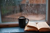 Fototapeta  - cup with an open book beside it on a windowsill during a downpour