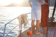 Couple in love sailing on yacht at sunset in summer. Sea vacation. Happy man and woman hugging and traveling. Intimate date on holiday. Romantic lifestyle. Close-up of barefoot legs on wooden deck