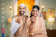 Happy indian muslim couple wishing for ramadan festival by saying with hand gesture by looking at camera - concept of islamic festival, togetherness and festive greeting.