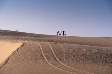 Wall Mural - Aerial view of a peasant woman carries a bamboo frame on the shoulder across sand dunes in Ninh Thuan province, Vietnam. It is one of the most beautiful places in Vietnam