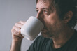 Unkempt man drinking morning coffee from a white mug
