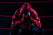 The athlete sits in a chair in the boxing ring after losing the fight. Despite the technical preparation, the athlete lost the fight in a sweatshirt.