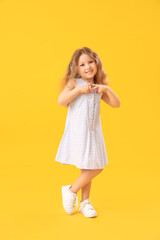 Sticker - Little girl making heart with her hands on yellow background. Children's Day celebration