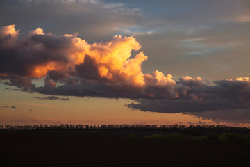 Wall Mural - dark storm clouds illuminated by the sun at sunset.