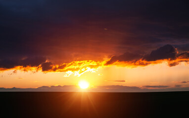 Wall Mural - dark storm clouds illuminated by the sun at sunset.