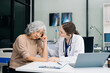 © Nuttapong punna - Portrait of female doctor explaining diagnosis to her patient. Doctor Meeting With Patient In Exam Room. A medical practitioner reassuring a patient