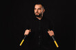 © Vulp - Studio portrait of a serious young man is mastering the art of nunchaku over dark backdrop.