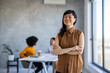 © Dragana Gordic - Head shot portrait smiling confident Asian businesswoman with arms crossed standing in modern office with colleagues on background, successful happy employee entrepreneur executive looking at camera