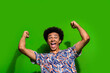 Photo of good mood impressed man dressed print shirt rising fists screaming yeah isolated green color background