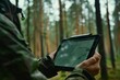 close-up a person's hands holding a digital tablet displaying a map,sunlit forest in the background