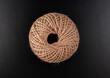 A brown ball of yarn is sitting on a black surface. The yarn is twisted and knotted, giving it a rough and unkempt appearance. Concept of nostalgia and simplicity, as the yarn represents a basic