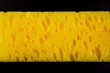 A yellow sponge with a black background. The sponge is yellow and has a lot of bumps on it