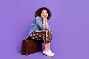 Wall Mural - Full body portrait of pretty young woman sit valise empty space wear denim shirt isolated on purple color background