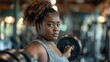 Determined woman lifting weights in gym with focused expression