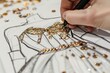 closeup of designers hand adding sequins to a dress sketch
