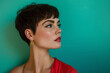 Stylish woman dons a trendy pixie haircut, showcased tastefully on a vibrant teal backdrop