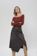 Serie of studio photos of female model in brown shirt and leather midi skirt and high knee boots, autumn winter fashion collection.