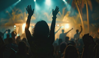 Woman with an uplifted hand against an illuminated concert stage backdrop. The concept of euphoria and musical enjoyment.