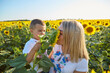 Happy mother and son in Ukrainian clothes - embroiderers in a field of sunflowers.