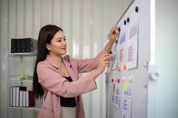 Wall Mural - Asian businesswoman or female financial analyst financial analysis and investment plan on a board at office