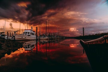 Wall Mural - Ominous landscape featuring multiple boats, illuminated by the orange hues of the sunset