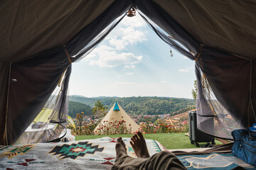 male traveler relaxing and enjoying with the mountain, local village view inside camping tent on vac