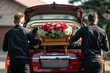 Bearers are carrying a coffin in a mourning car