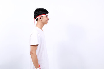 Side view of young asian boy with red white ribbon celebrating Indonesia independence day. Isolated on white background with copyspace