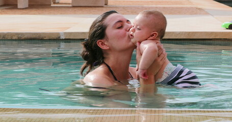 Wall Mural - Happy loving young mother at the swimming pool water with newborn baby infant son